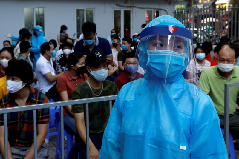 A healthcare worker wearing protective suit walks past as local residents wait at a coronavirus disease (covid-19) testing center in hanoi, vietnam aug 10, 2020. (reuters) 